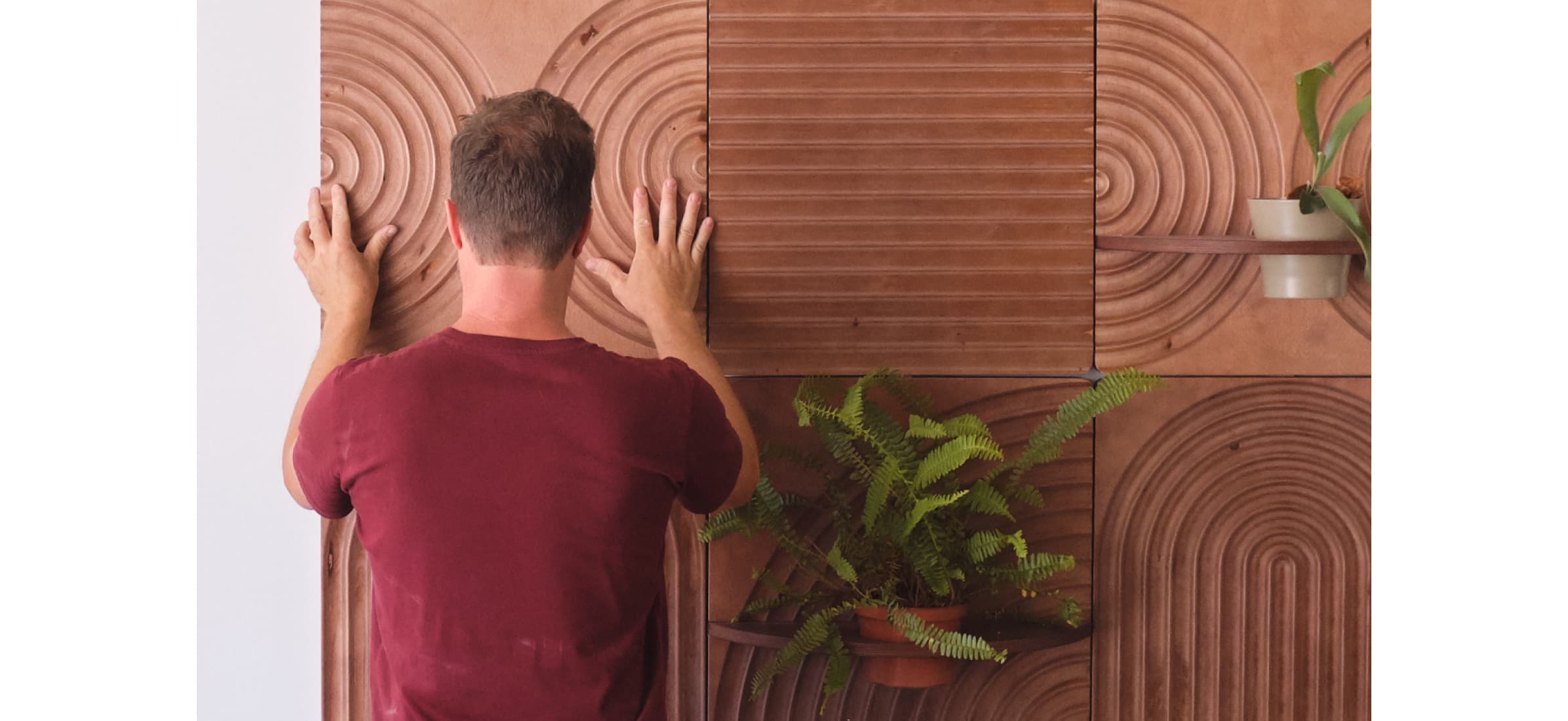 Aaron installing the last of six patterned terracotta panels onto a wall.